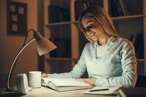 Young blonde woman studying at night photo