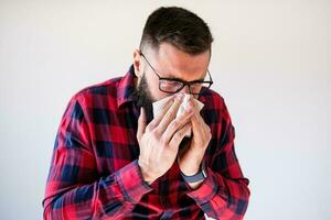 Portrait of a man in red and blue plaid shirt blowing his nose photo