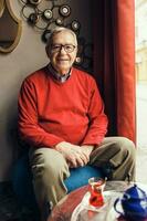 A senior man in a red sweater relaxing photo