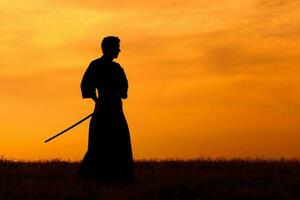 Silhouette of kendo fighter with shinai over the sunset photo