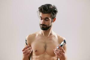 An indecisive man holding a razor and an electric shaver photo