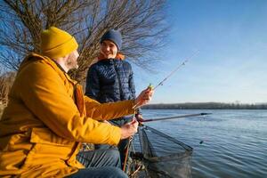 Father and son are fishing on sunny winter day photo