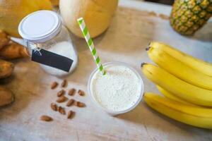 Healthy protein shake on table with fruits and vegetables ingredients around photo