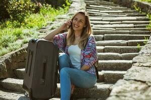 joven turista mujer sentado por el escalera con un maleta foto