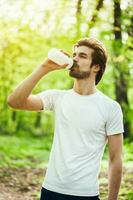 un hombre Bebiendo agua después haciendo físico ejercicios foto