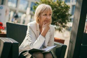 A senior businesswoman sitting at a cafe photo