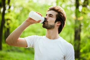A man drinking water after doing physical exercises photo