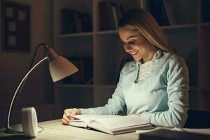 Young blonde woman studying at night photo