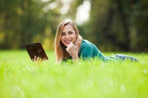 un mujer gasto hora al aire libre con un tableta dispositivo foto