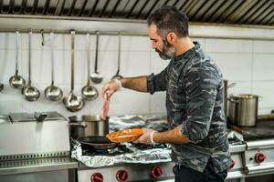 un cocinero es preparando un comida en el restaurante cocina. foto