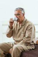 A senior man in his bedroom with coffee photo