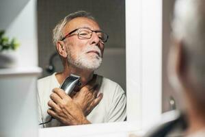 A senior man trims his beard photo