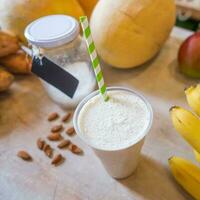 Healthy protein shake on table with fruits and vegetables ingredients around photo