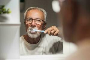 un mayor hombre cepillos su dientes foto