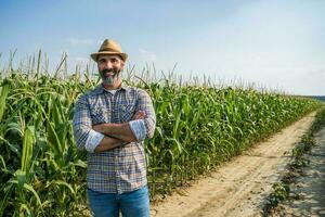 orgulloso granjero es en pie en su creciente maíz campo foto