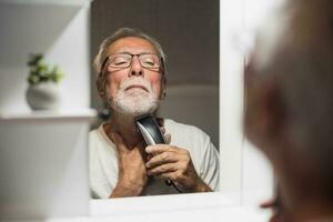 A senior man trims his beard photo