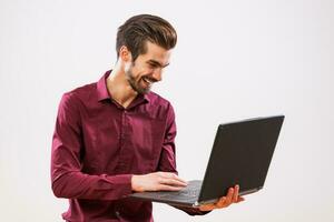 un hombre en un púrpura camisa con un ordenador portátil foto