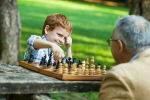 A grandfather and his grandson playing chess photo