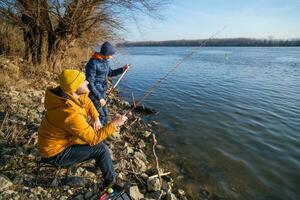 Father and son are fishing on sunny winter day photo