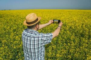 A farmer examining a rapeseed field photo