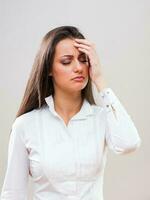un mujer en un blanco camisa con un dolor de cabeza foto