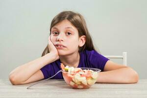 un niña comiendo un Fruta ensalada foto