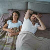 A young couple lying in bed with relationship issues photo