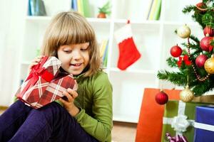 A young girl opening a Christmas present photo