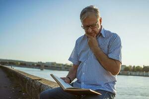 Senior man reading a book outside photo