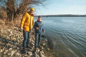 Father and son are fishing on sunny winter day photo