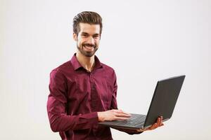 un hombre en un púrpura camisa con un ordenador portátil foto