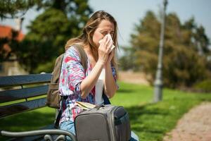 Young tourist woman blowing her nose on the park photo