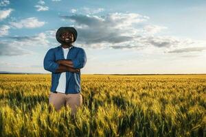 afro granjero en pie en un trigo campo foto