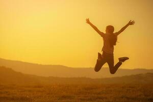 A girl jumping over the sunset photo