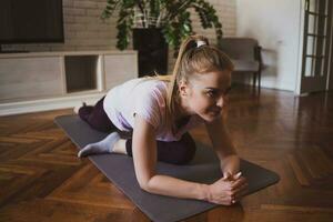 joven mujer practicando pilates y yoga ejercicios a hogar foto