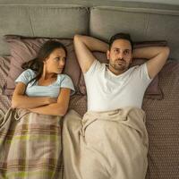 A young couple lying in bed with relationship issues photo