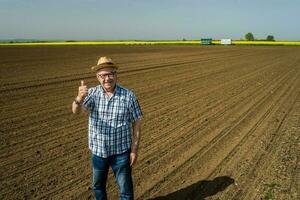 un mayor granjero en pie en su propio maíz campo foto