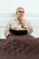 A senior man in his bedroom with a book photo