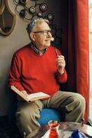 A senior man in a red sweater relaxing photo