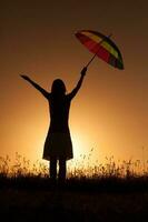 Silhouette of a woman with umbrella over the sunset photo