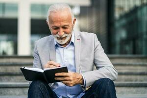 A senior businessman writing in a notebook photo