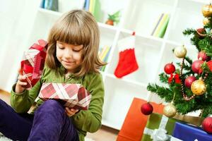 A young girl opening a Christmas present photo