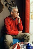 A senior man in a red sweater relaxing photo