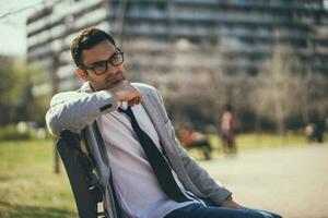 A businessman sitting on a park bench photo