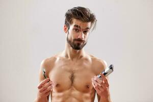 An indecisive man holding a razor and an electric shaver photo