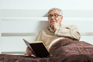 un mayor hombre en su dormitorio con un libro foto