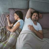 A young couple lying in bed with relationship issues photo