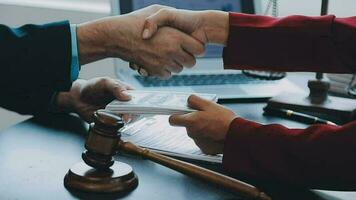 Justice and Law concept. Legal counsel presents to the client a signed contract with gavel and legal law or legal having team meeting at law firm in background video