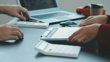 Closeup of Asian female signing car insurance document or lease paper contract or agreement. Buying or selling new or used vehicle with car keys on table. video