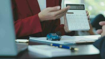 Closeup of Asian female signing car insurance document or lease paper contract or agreement. Buying or selling new or used vehicle with car keys on table. video